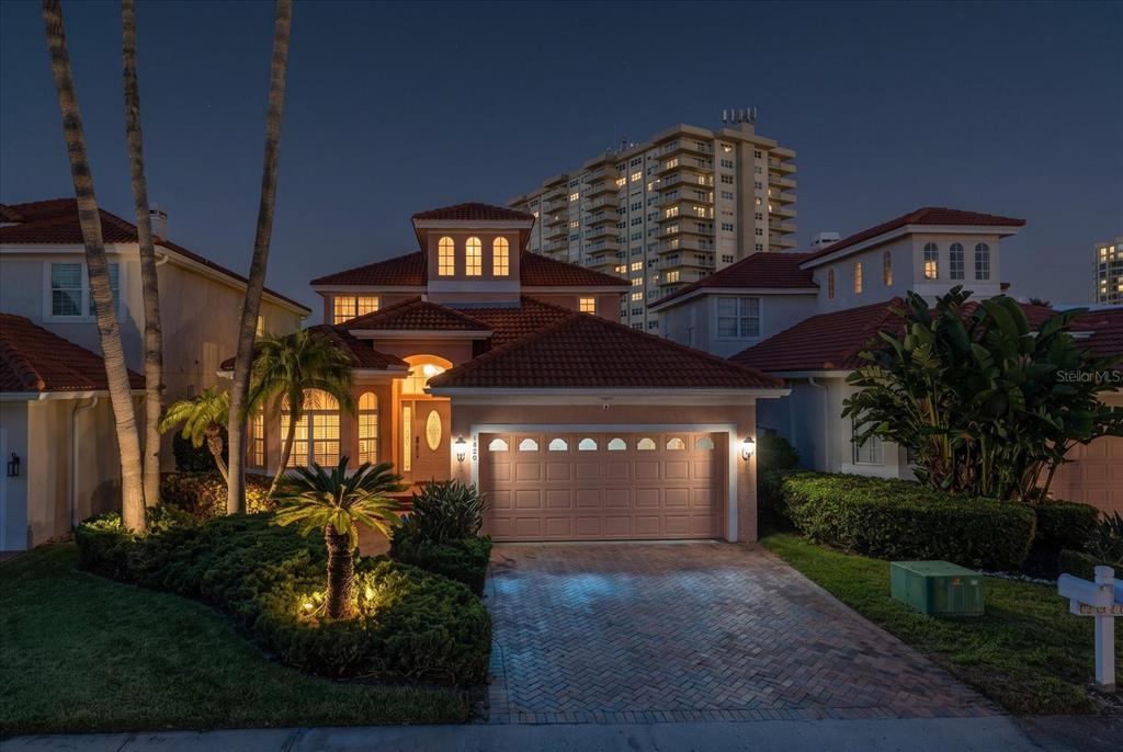 A two-story house with a tiled roof, a two-car garage, and a brick driveway at night — 1620 SAND KEY ESTATES COURT, CLEARWATER BEACH, FL