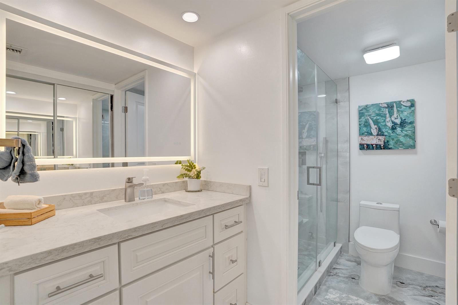 A bathroom features a white vanity with a marble countertop, a glass shower, and toilet — 1211 Bahama Bend # E1, Coconut Creek FL 33066, COCONUT CREEK, FL