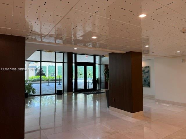 A modern building lobby features a glossy white ceiling, polished tile floors, and glass doors — 540 Brickell Key Dr # 1024, Miami FL 33131, MIAMI, FL