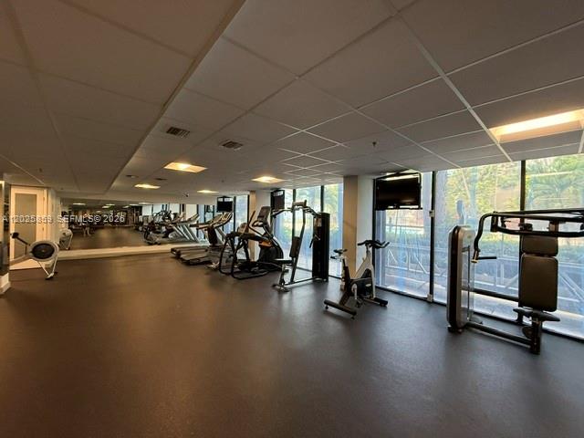 A gym features various exercise machines, mirrored walls, and a drop ceiling with recessed lighting — 540 Brickell Key Dr # 1024, Miami FL 33131, MIAMI, FL