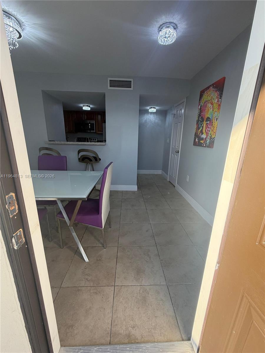 A dining area with a glass table and purple chairs opens into a kitchen — 1955 NW 5th Pl # 13, Miami FL 33136, MIAMI, FL