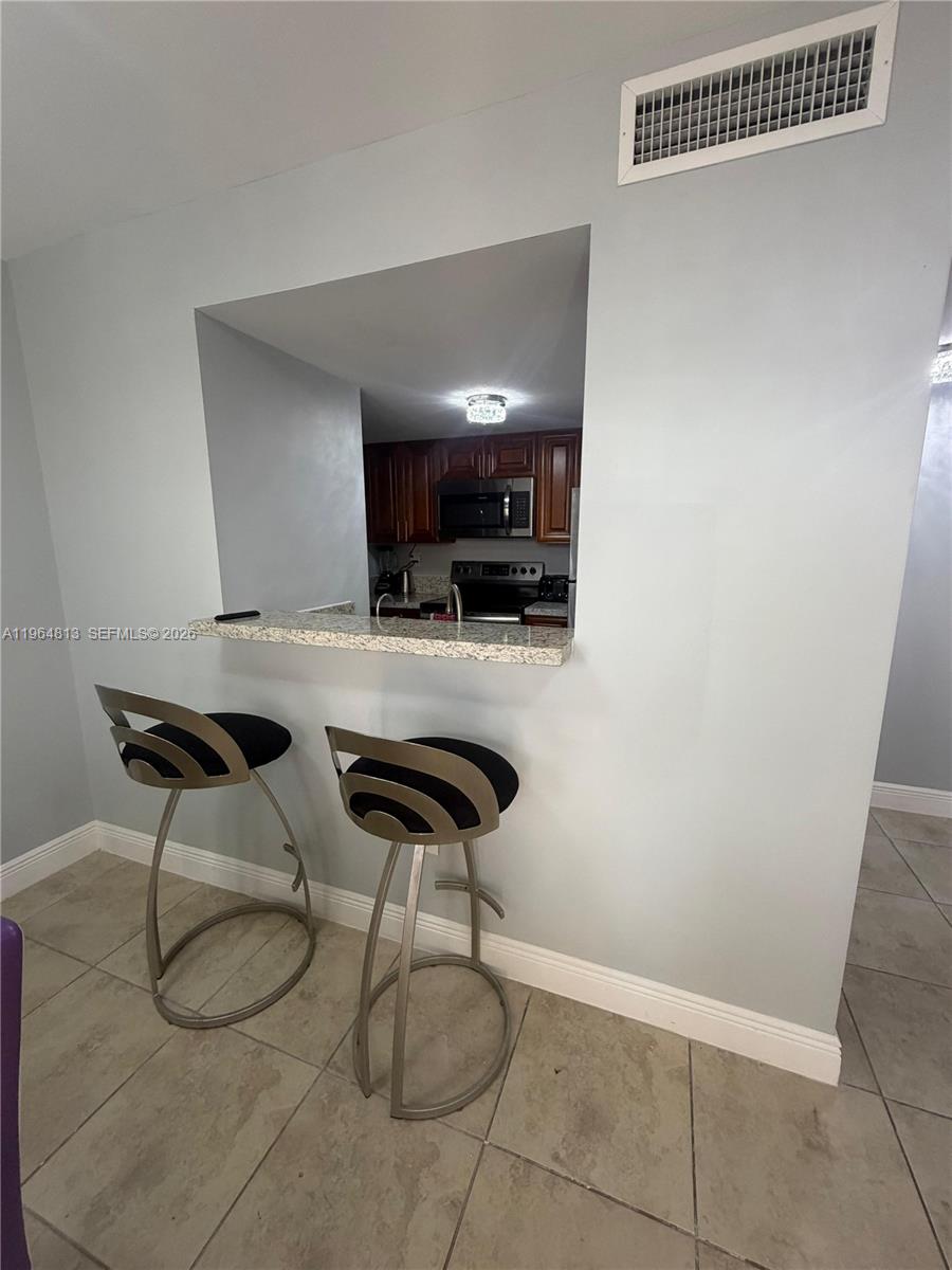 A kitchen pass-through window features a granite countertop and two modern bar stools — 1955 NW 5th Pl # 13, Miami FL 33136, MIAMI, FL