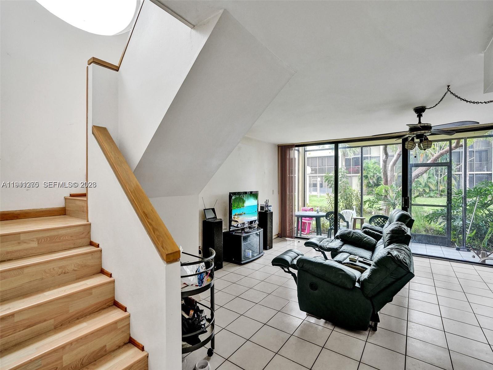A living room features tiled floors, a wooden staircase, and a sliding glass door — 2910 SW 87th Ter # 1701, Davie FL 33328, DAVIE, FL
