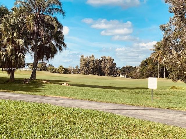 A paved path winds through a grassy golf course with palm trees under a blue sky — 16171 Blatt Blvd # 101, Weston FL 33326, WESTON, FL