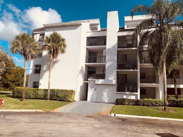 A multi-story white apartment building features balconies and palm trees under a blue sky — 16171 Blatt Blvd # 101, Weston FL 33326, WESTON, FL