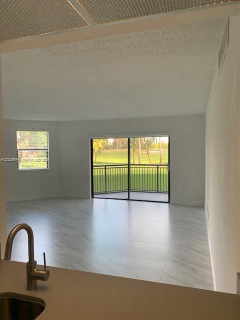 A view from a kitchen sink looking into a living room with tile floors and balcony — 16171 Blatt Blvd # 101, Weston FL 33326, WESTON, FL