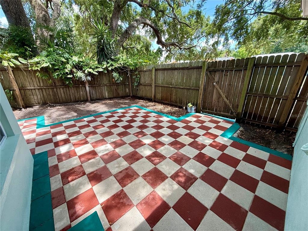 A backyard patio features a red and white checkered tile floor bordered by green paint — 677 OAKWOOD DRIVE, DUNEDIN, FL
