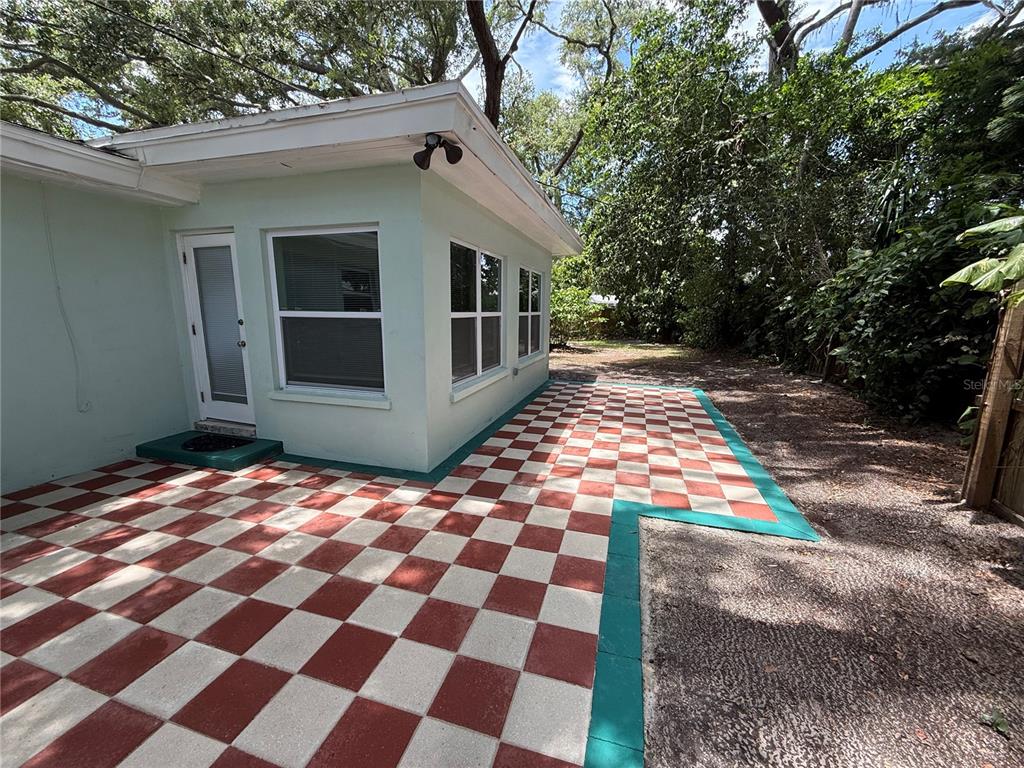 A light green house exterior features a red and white checkered patio with teal borders — 677 OAKWOOD DRIVE, DUNEDIN, FL