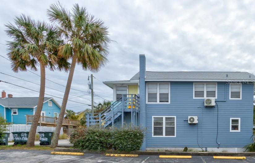 A blue two-story house with an exterior staircase, palm trees, and a parking lot — 124 S NOBLE, DAYTONA BEACH, FL