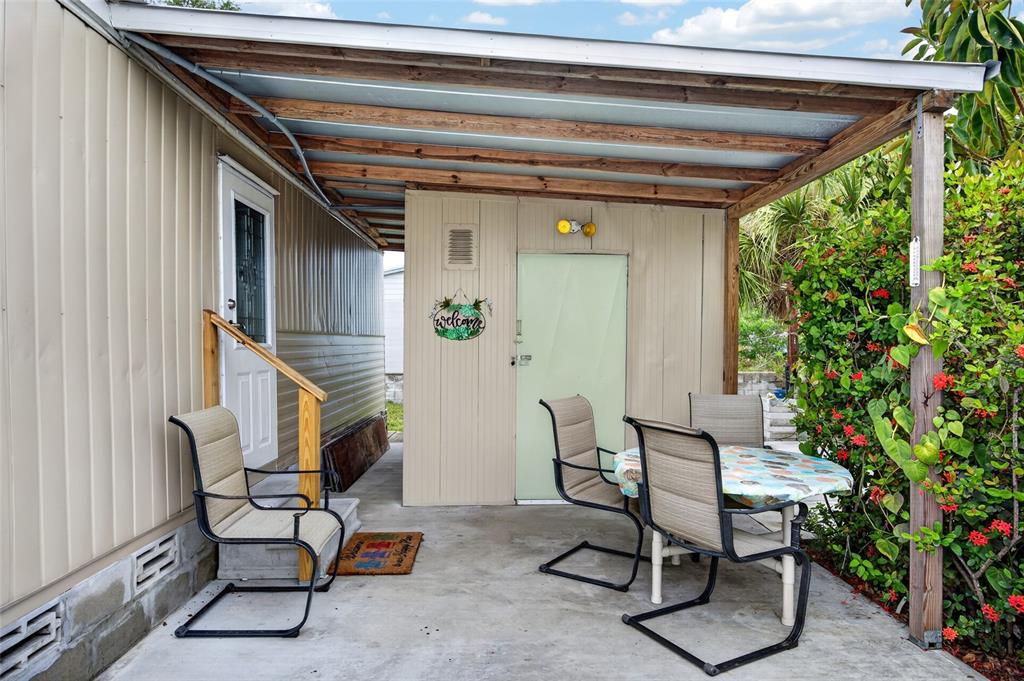 A covered concrete patio features a dining set and a doorway with a welcome sign — 3160 10TH STREET, ENGLEWOOD, FL