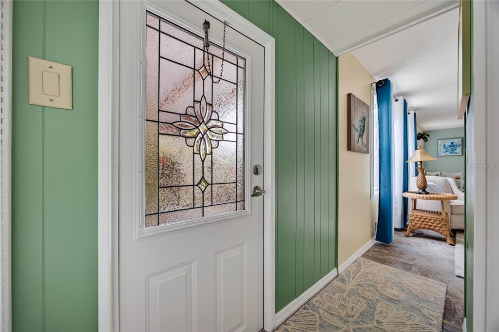 An entryway features a white door with a decorative glass panel and green paneled walls — 3160 10TH STREET, ENGLEWOOD, FL