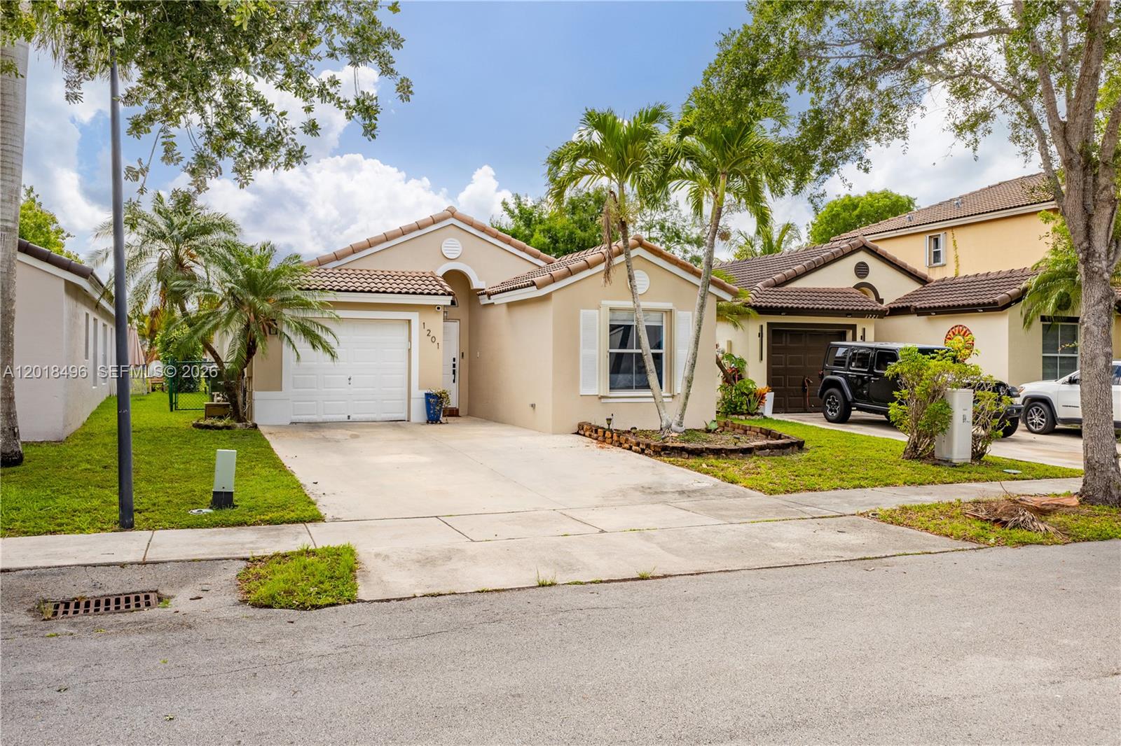 A single-story tan house with a tile roof, garage, and palm trees in the front yard — 1201 SE 20th Rd, Homestead FL 33035, HOMESTEAD, FL