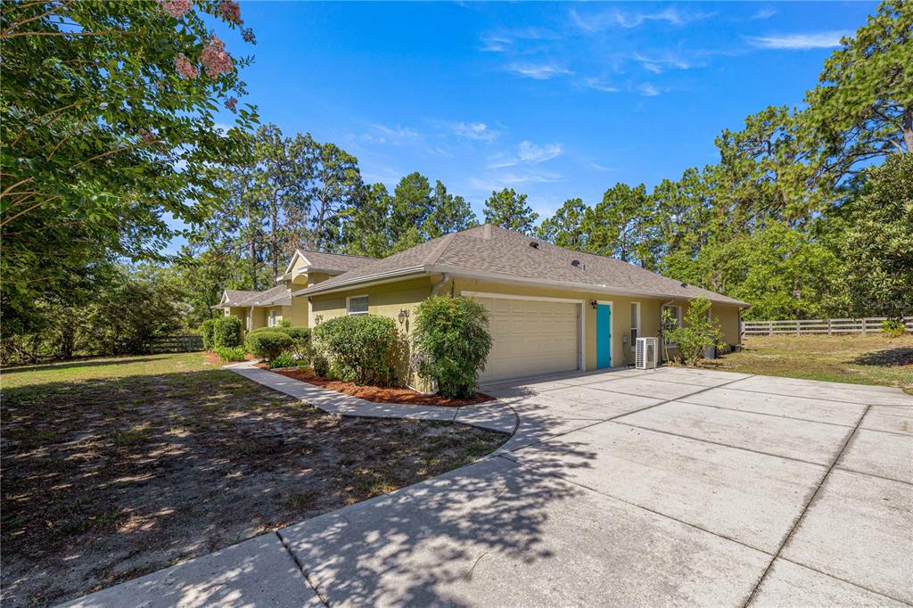 A tan house with a two-car garage, a bright blue door, and a concrete driveway — 4890 W GEYSER COURT, BEVERLY HILLS, FL