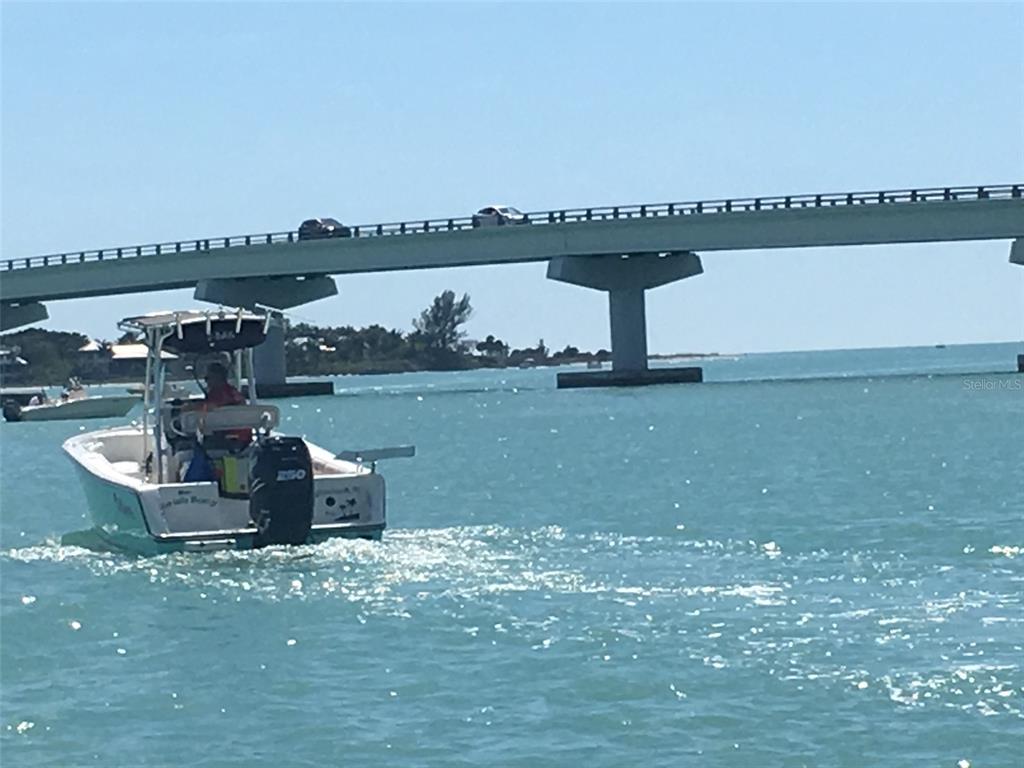 A motorboat travels on the water beneath a long concrete bridge under a clear sky — 4075 GILLOT BOULEVARD, PORT CHARLOTTE, FL