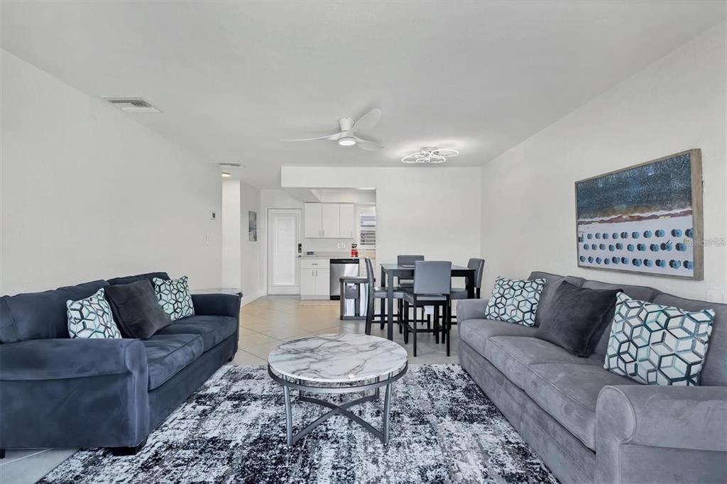 A living room features two sofas, a marble coffee table, and an adjacent dining area — 5830 MIDNIGHT PASS ROAD UNIT 54, SARASOTA, FL