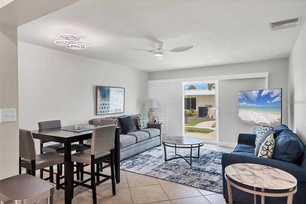 A living and dining area features tile floors, a ceiling fan, and a sliding glass door — 5830 MIDNIGHT PASS ROAD UNIT 54, SARASOTA, FL