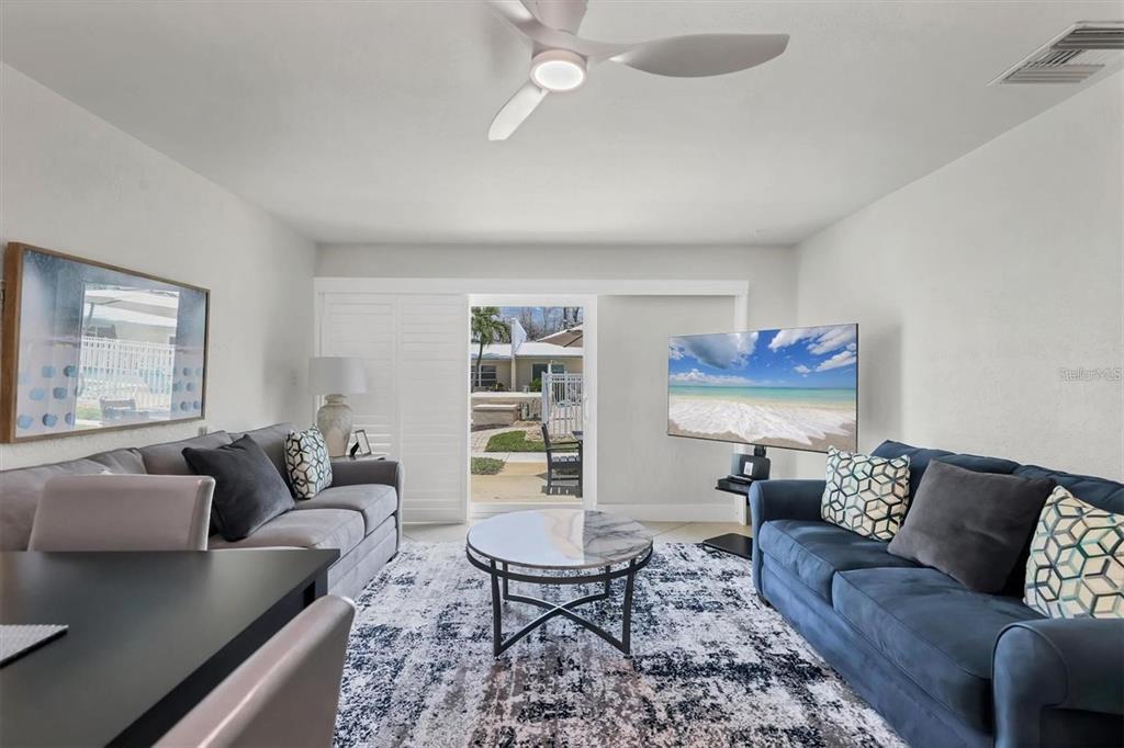 A living room features two sofas, a marble coffee table, and a sliding glass door — 5830 MIDNIGHT PASS ROAD UNIT 54, SARASOTA, FL