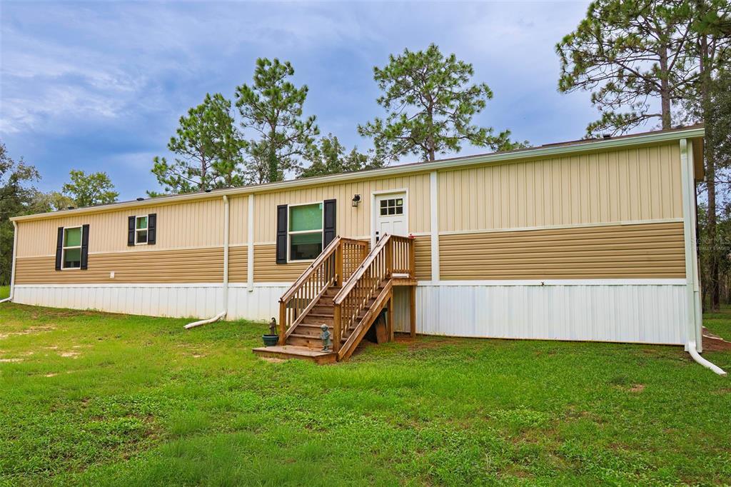 A single-story manufactured home with tan and cream siding and wooden stairs leading to the entrance — 6556 S LIMA AVENUE, HOMOSASSA, FL