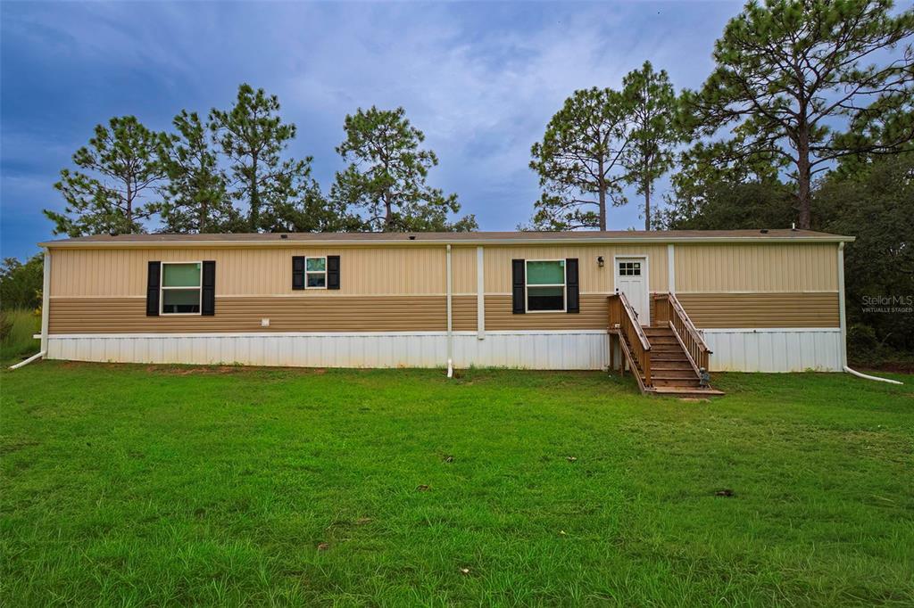A single-story manufactured home with tan and brown siding sits on a grassy lot — 6556 S LIMA AVENUE, HOMOSASSA, FL