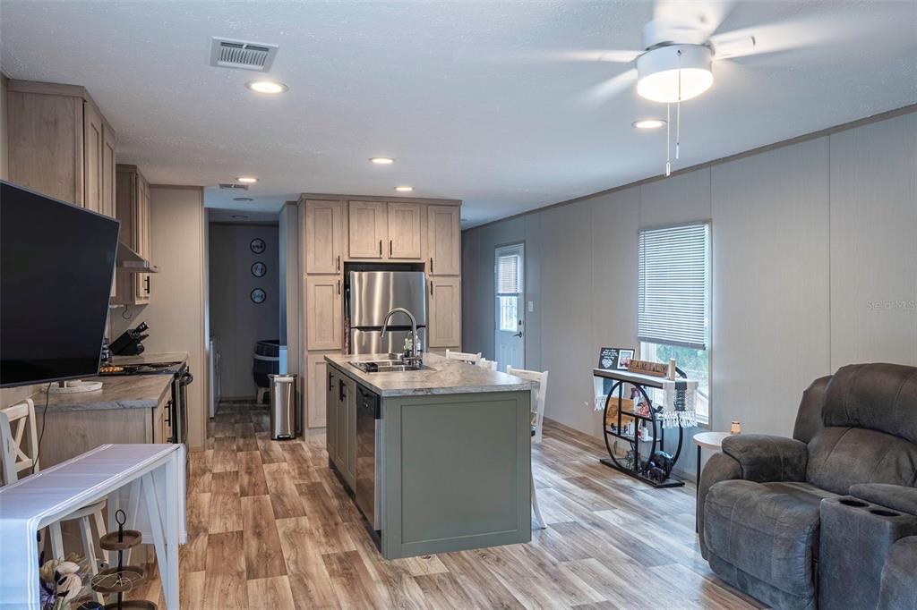 A kitchen with a gray island, stainless steel appliances, and wood-look flooring in an open room — 6556 S LIMA AVENUE, HOMOSASSA, FL