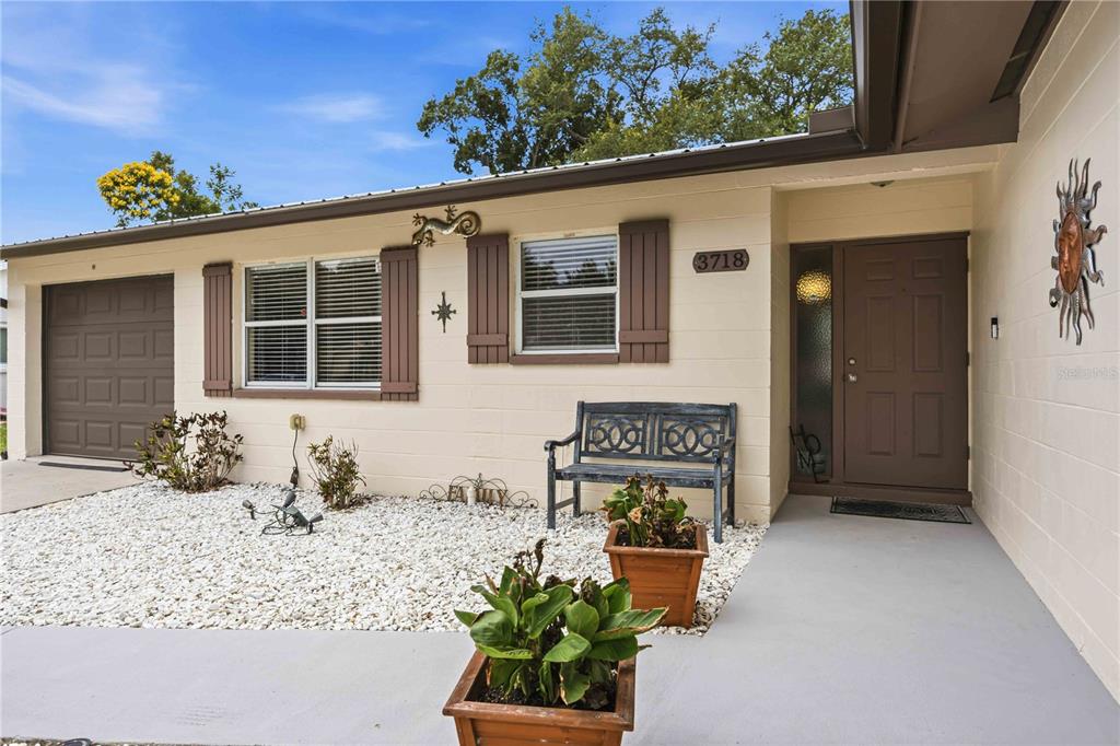 The exterior of a single-story house features a brown front door, shutters, and gravel landscaping — 3718 WOODMONT DRIVE, SARASOTA, FL