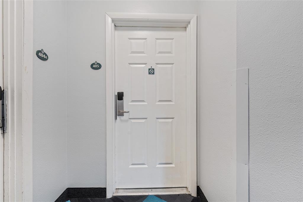 A white door with a digital lock and room number 405 in a hallway — 300 N ATLANTIC AVENUE UNIT 405, DAYTONA BEACH, FL
