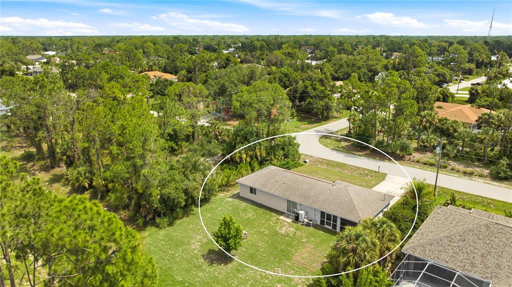 An aerial view shows a single-story house with a tan roof and a large backyard — 1167 URMEY LANE, NORTH PORT, FL