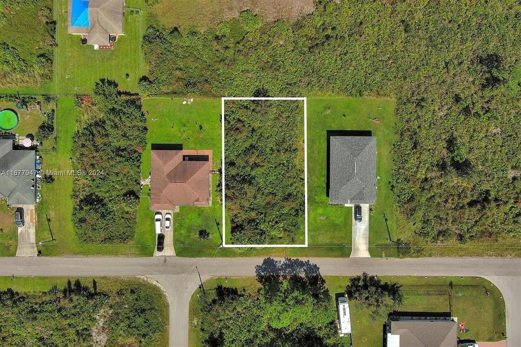 An aerial view shows a vacant, rectangular residential lot situated between two existing houses — 2912 61ST STREET W, LEHIGH ACRES, FL