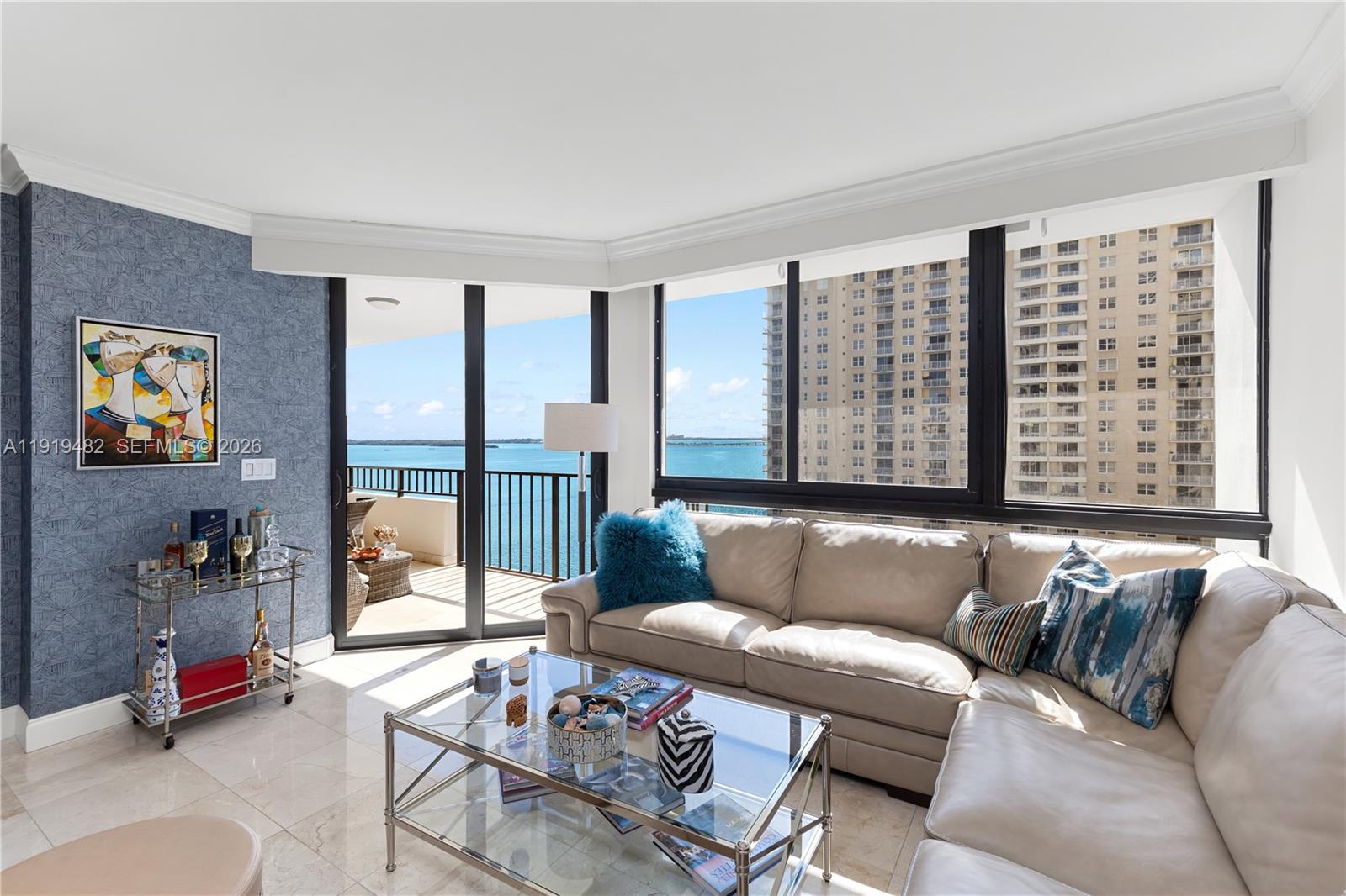 A living room features a beige sectional sofa, glass coffee table, and balcony with water views — 520 Brickell Key Dr # A1207, Miami FL 33131, MIAMI, FL