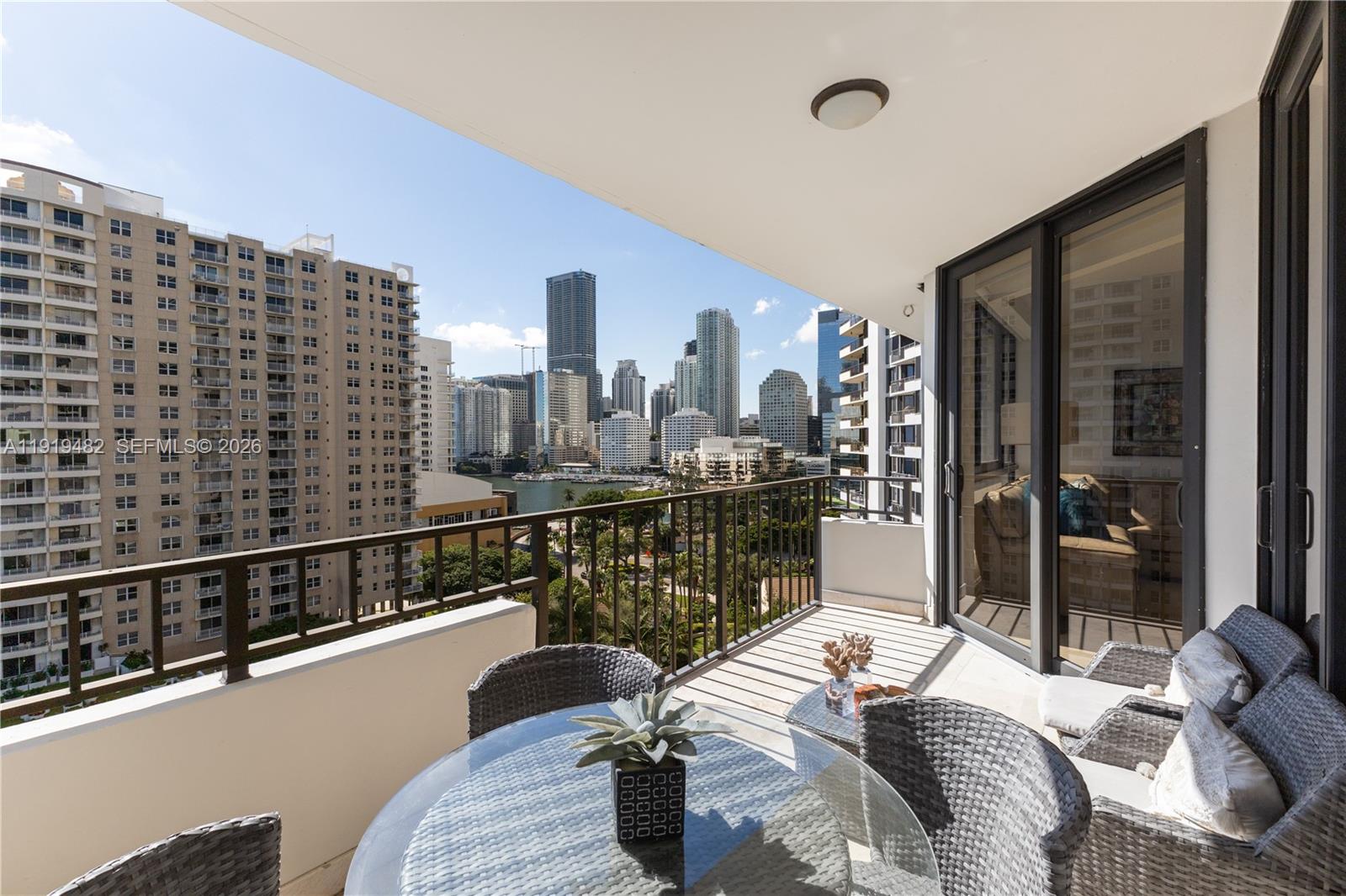 A balcony with outdoor furniture overlooks a city skyline and a body of water — 520 Brickell Key Dr # A1207, Miami FL 33131, MIAMI, FL
