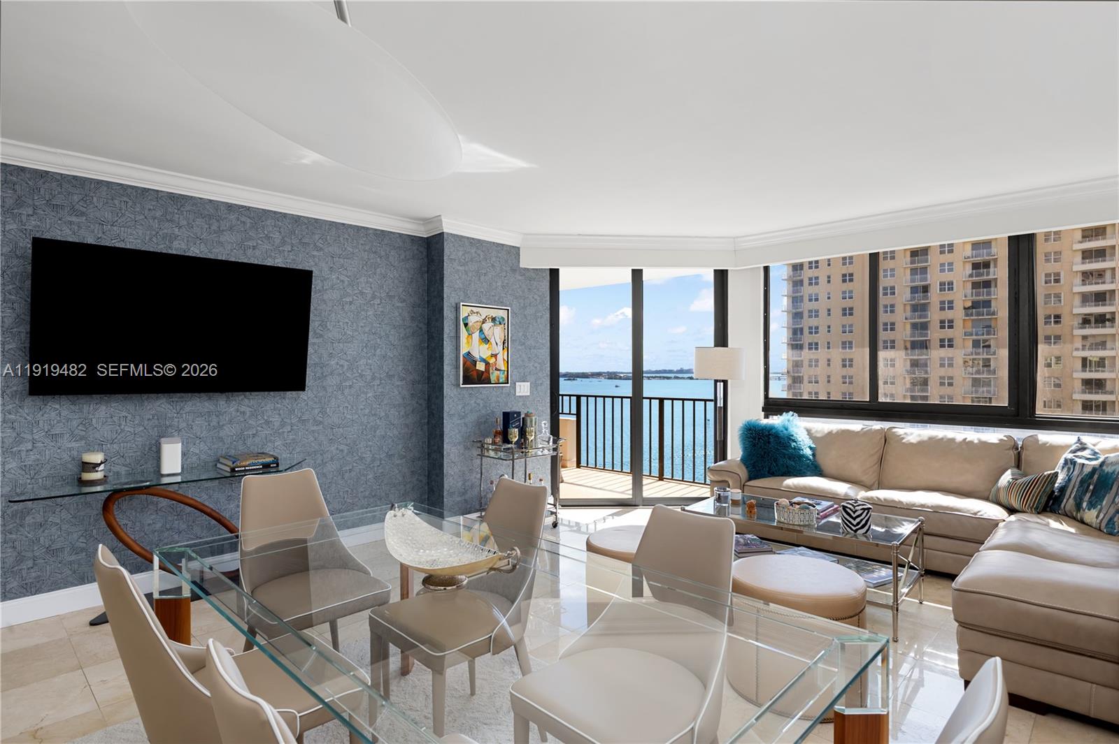 A living and dining room features blue textured wallpaper, a glass table, and balcony views — 520 Brickell Key Dr # A1207, Miami FL 33131, MIAMI, FL