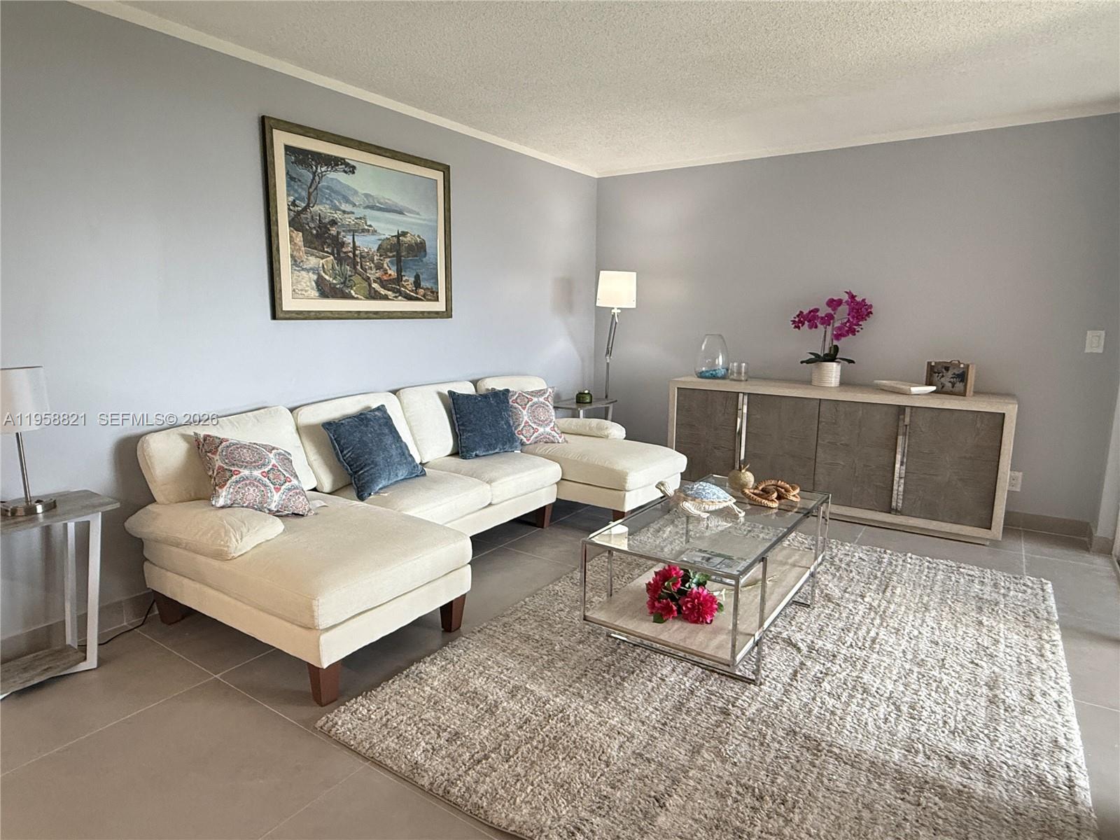 A living room features a white sectional sofa, a glass coffee table, and a sideboard — 950 Egret Cir # 5409, Delray Beach FL 33444, DELRAY BEACH, FL