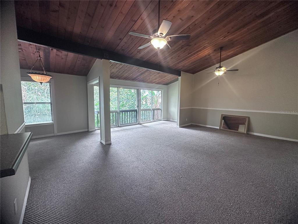 A living room features a vaulted wood-paneled ceiling, carpeted flooring, and sliding glass balcony doors — 200 MAITLAND AVENUE UNIT 224, ALTAMONTE SPRINGS, FL