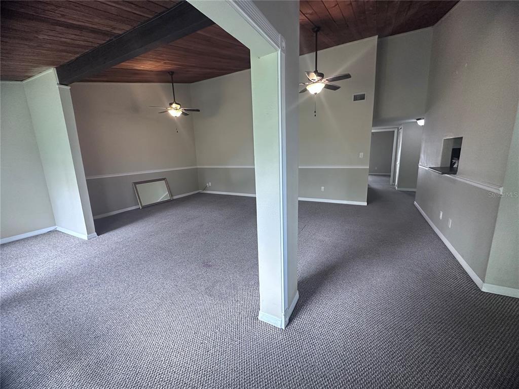 An interior view shows a carpeted living area with a wood-paneled ceiling and ceiling fans — 200 MAITLAND AVENUE UNIT 224, ALTAMONTE SPRINGS, FL