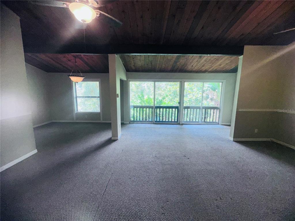 A living room features a vaulted wood-plank ceiling, gray carpeting, and large sliding glass doors — 200 MAITLAND AVENUE UNIT 224, ALTAMONTE SPRINGS, FL