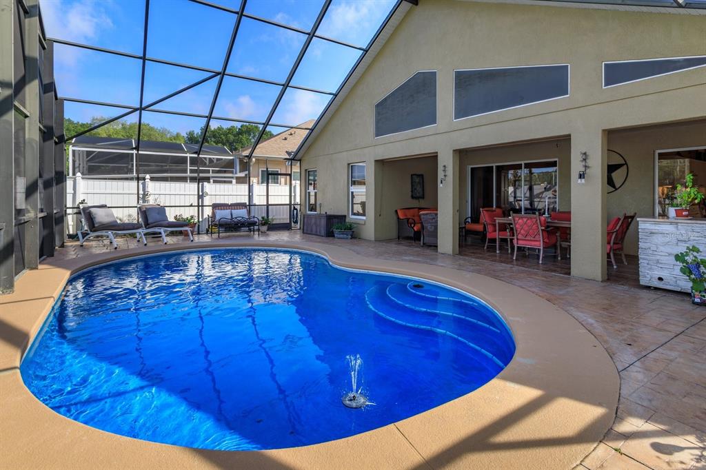 A screened-in patio features a swimming pool with a fountain and outdoor dining furniture — 2505 ARRAN CT, CLERMONT, FL