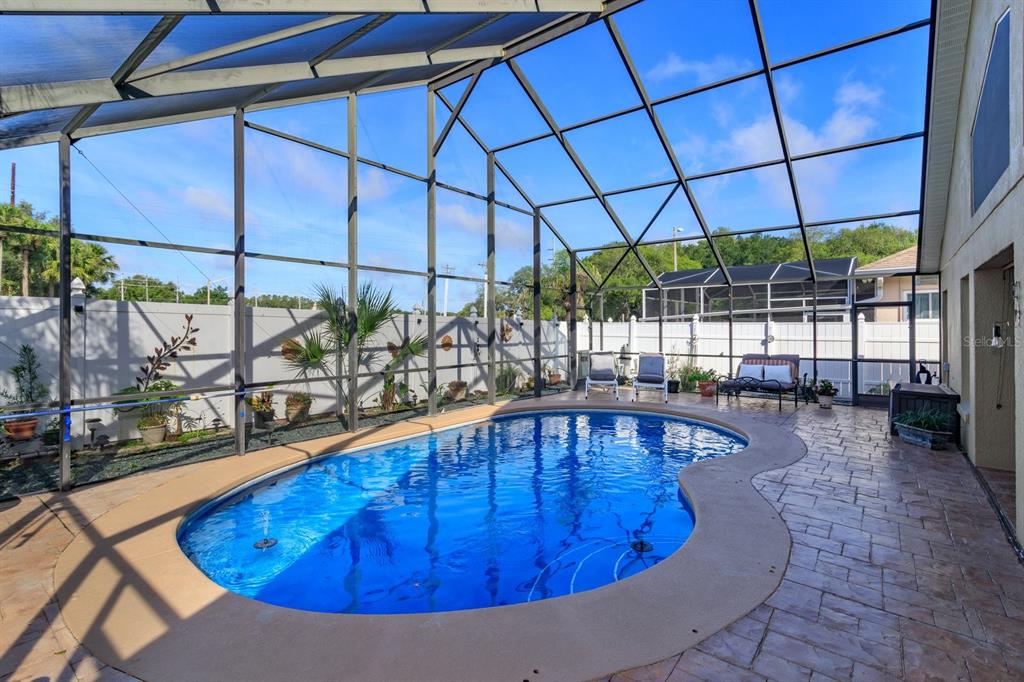 A screened-in patio features a kidney-shaped swimming pool and a stamped concrete deck — 2505 ARRAN CT, CLERMONT, FL