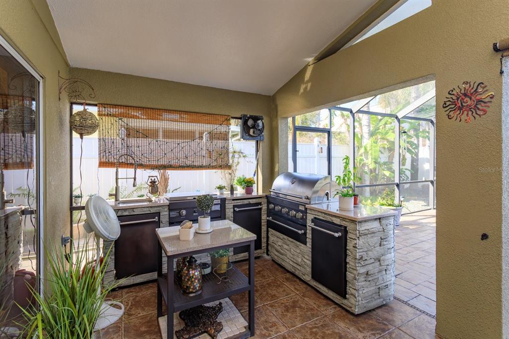 An outdoor kitchen features stone-faced cabinets, a stainless steel grill, and a small island — 2505 ARRAN CT, CLERMONT, FL