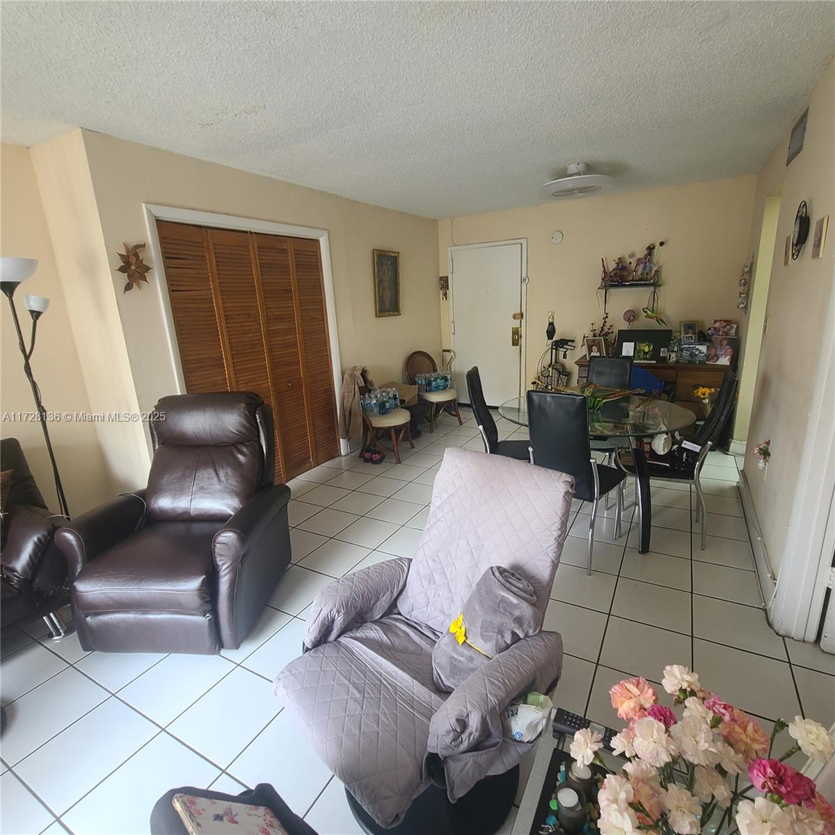 A living and dining area features tiled floors, a brown recliner, and a glass dining table — 4803 NW 7th St # 14, Miami FL 33126, MIAMI, FL