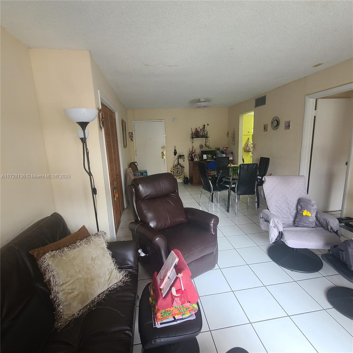 A living room features white tile flooring, a brown leather recliner, and a dining area — 4803 NW 7th St # 14, Miami FL 33126, MIAMI, FL