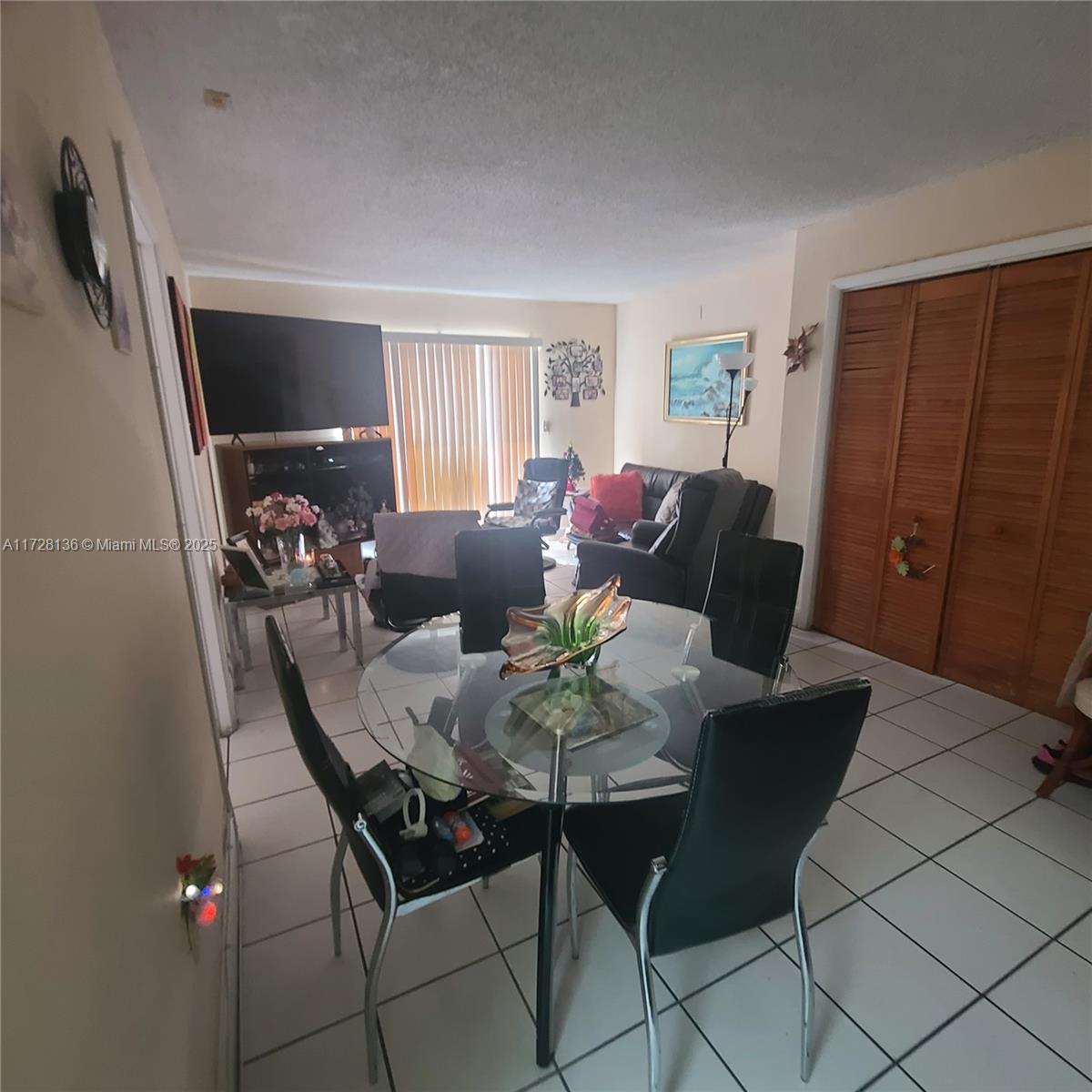 A dining area with a glass table and black chairs opens into a living room — 4803 NW 7th St # 14, Miami FL 33126, MIAMI, FL