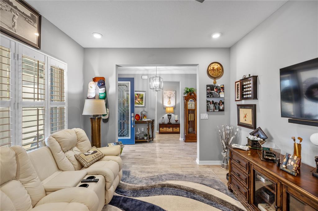 A living room features a white sofa, a wooden media console, and a view into the entryway — 9343 SW 102ND AVENUE ROAD, OCALA, FL