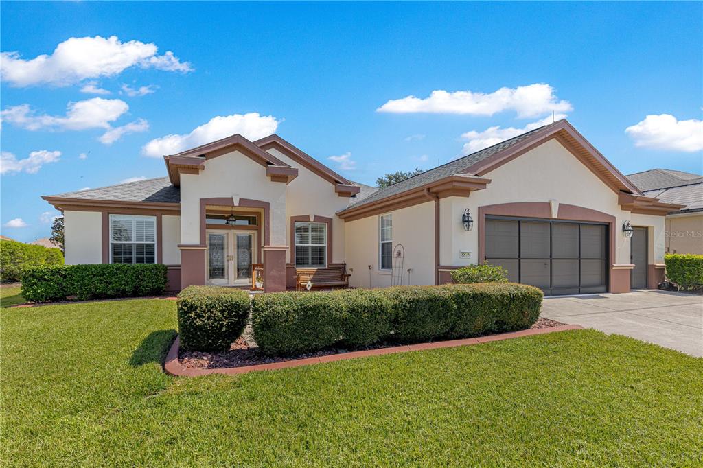A single-story house with a beige stucco exterior, brown trim, and a two-car garage — 8875 SE 132ND PLACE, SUMMERFIELD, FL