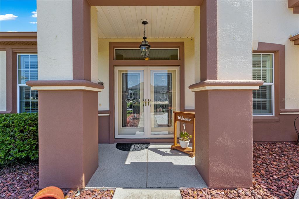 The front entrance features double glass doors, a hanging lantern, and a small welcome sign — 8875 SE 132ND PLACE, SUMMERFIELD, FL