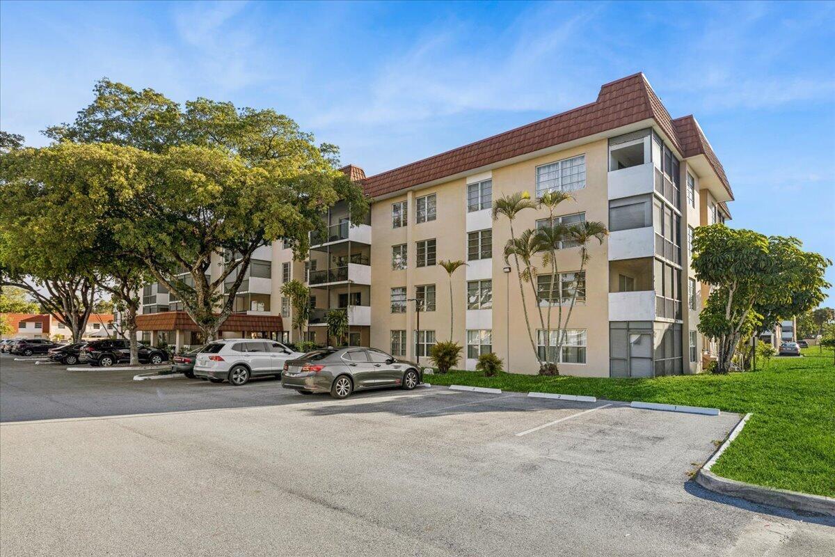 A multi-story apartment building with a parking lot in the foreground under a blue sky — 4156 Inverrary Drive, Lauderhill FL 33319, LAUDERHILL, FL