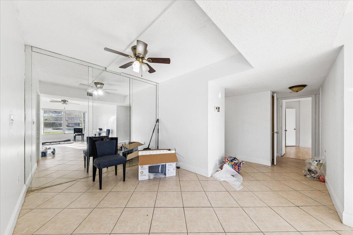 An empty room features beige tile flooring, a mirrored wall, and a ceiling fan — 4156 Inverrary Drive, Lauderhill FL 33319, LAUDERHILL, FL