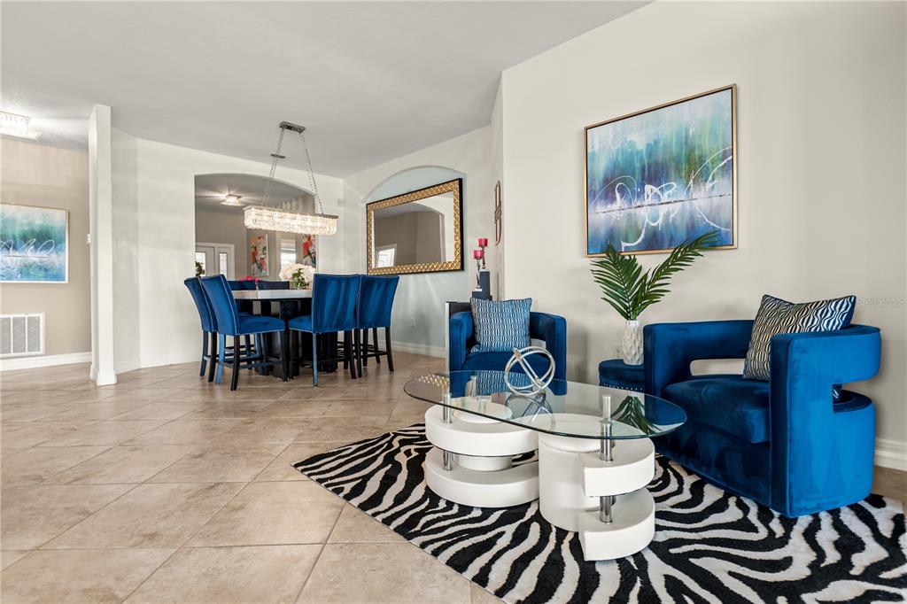 A living room with blue velvet chairs, a glass coffee table, and a zebra-print rug — 1375 PALMETTO DUNES STREET, DAVENPORT, FL