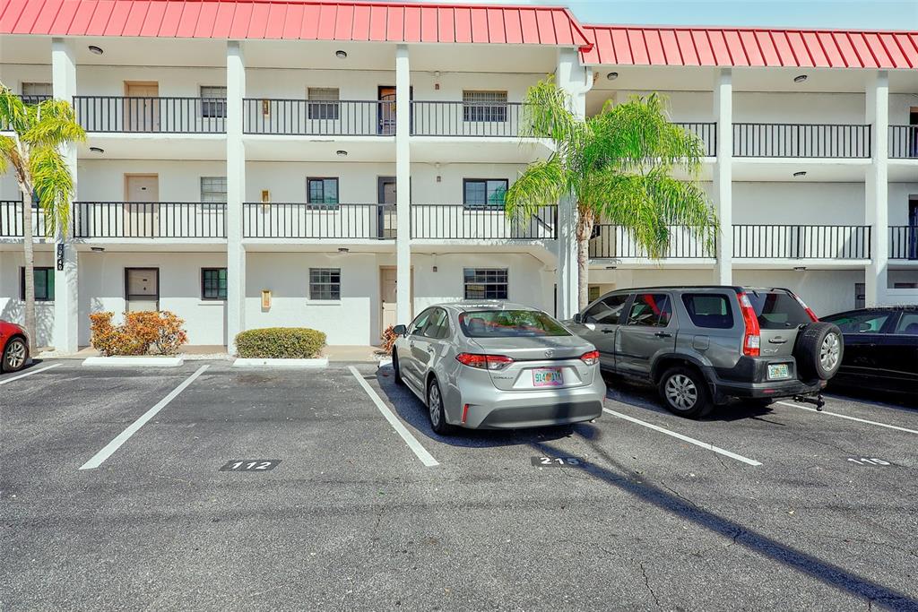 A three-story apartment building exterior features white walls, black railings, and a red roof — 10540 77TH TERRACE UNIT 109, SEMINOLE, FL