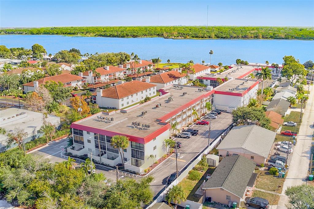 An aerial view shows a multi-story apartment complex with a red roof near a lake — 10540 77TH TERRACE UNIT 109, SEMINOLE, FL