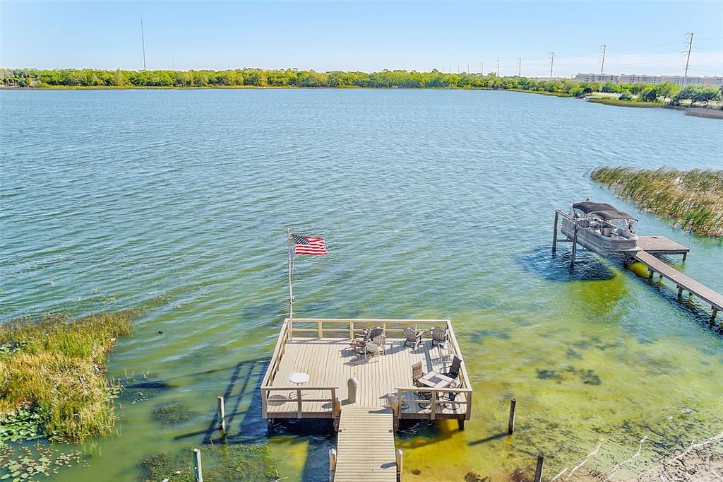An aerial view shows a wooden dock with chairs and a flag on a lake — 10540 77TH TERRACE UNIT 109, SEMINOLE, FL